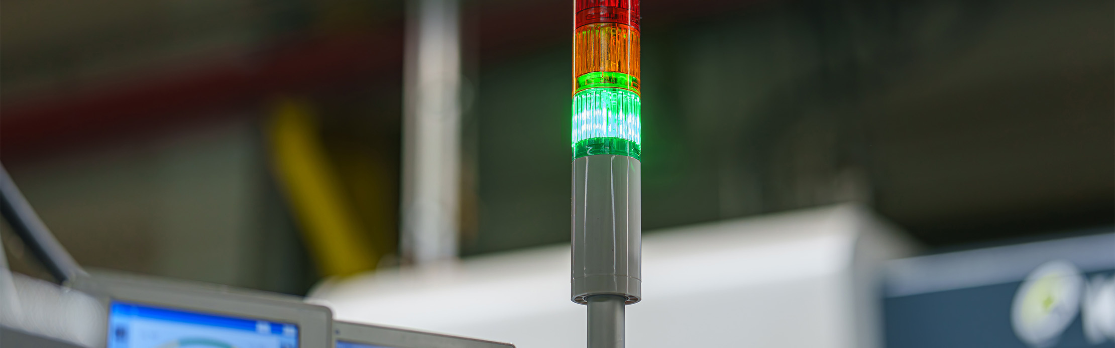 Leuchtende grüne Signalsäule an einer Maschine in einer industriellen Produktionshalle.