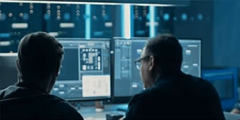 Das Bild zeigt zwei Entwickler vor Monitoren die an einer spannenden Entwicklung arbeiten.