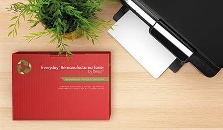 Das Bild zeigt die Aufsicht eines Schreibtisches auf der rechts ein Xerox Drucker im Anschnitt, unten links eine Every Day Toner Box und darüber dekorativ eine Grünpflanze abgebildet sind. Bei Klick auf das Bild wird die Unterseite "Every Day Toner für Drucker anderer Hersteller" aufgerufen.