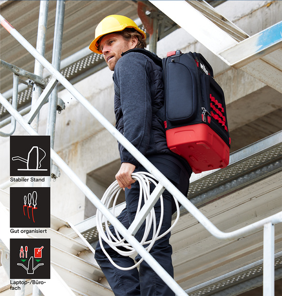 Mann mit gelbem Schutzhelm trägt Wiha Werkzeugrucksack und Kabelrolle auf einer Baustelle.