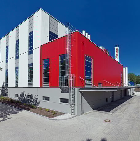  Ein modernes Knipex-Gebäude mit roter und weißer Fassade unter einem klaren blauen Himmel.