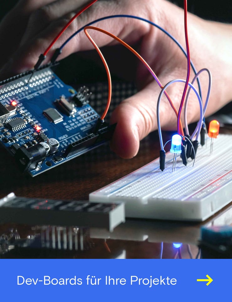 Eine Hand hält ein Entwicklungsboard während auf einer Steckerplatine eine blaue Lampe leuchtet