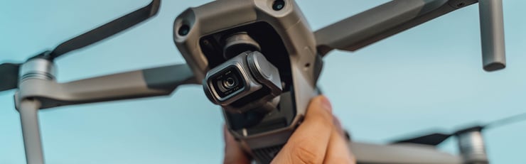 Eine Person hält eine Drohne mit Kamera in der Hand, bereit zum Abflug.