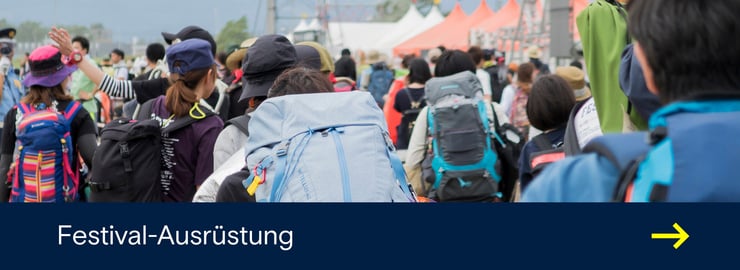Festivalbesucher mit grossen Rucksäcken gehen über ein Festivalgelände mit dem Schriftzug ‚Festival-Ausrüstung‘.