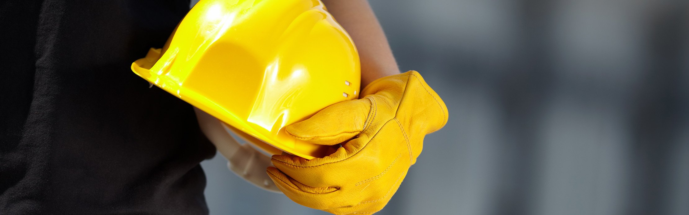 Ein Arbeiter mit einem gelbem Schutzhelm und gelben Schutzhandschuhen