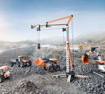 Ein großer orangefarbener Baukran von fischertechnik in einer Baustellen-Szene. Mehrere kleine Bauroboter und Fahrzeuge sind in der Umgebung zu sehen.