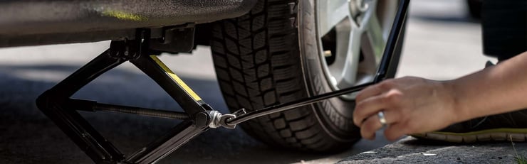 Eine Person hebt gerade ein Auto an, um die Reifen zu wechseln