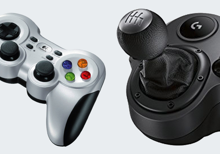 Silberner Logitech-Gamecontroller mit farbigen Tasten neben einem schwarzen Schalthebel für Rennspiele.