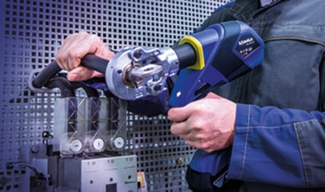 Ein Elektriker bedient ein akkubetriebenes hydraulisches Presswerkzeug, um eine Verbindung an einer Elektroinstallation vorzunehmen.