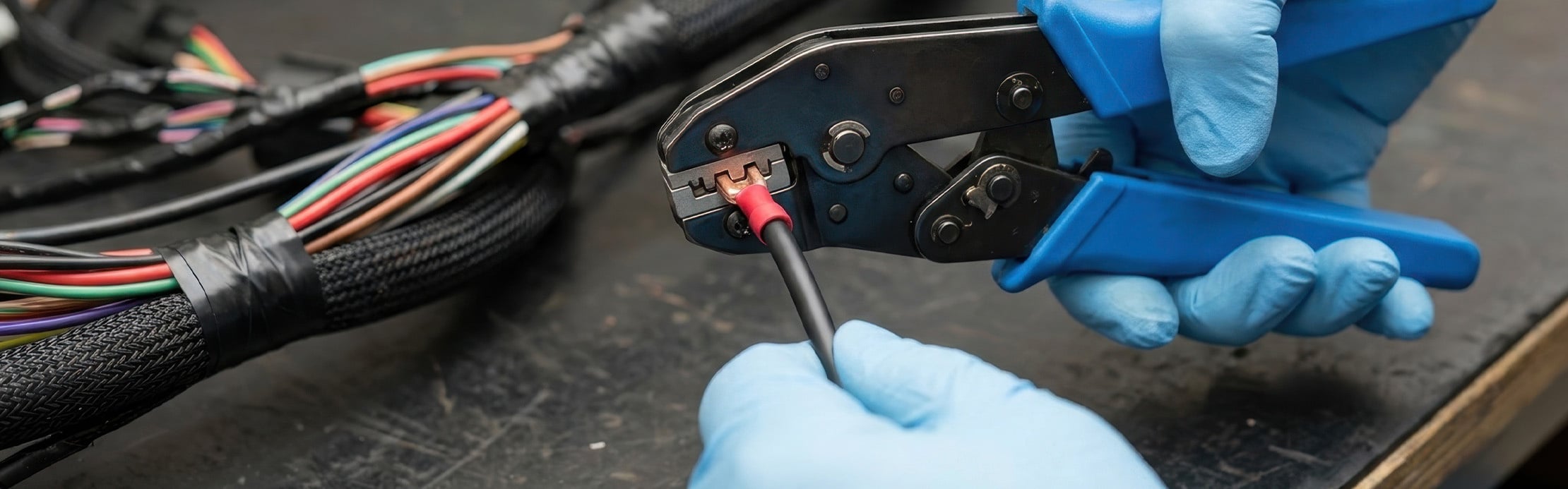 Person verpresst mit einer Crimpzange einen Kontakt an einem elektrischen Kabel