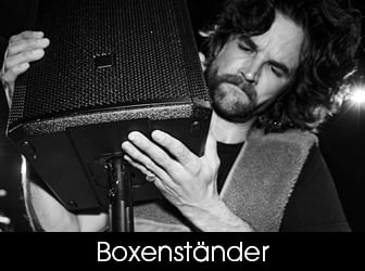 Eine Schwarz-Weiß-Nahaufnahme eines Mannes, der eine Lautsprecherbox auf das Rohr eines Boxenstativs montiert.