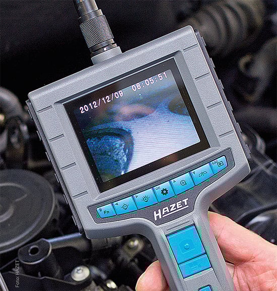 Ein Handheld-Endoskop der Marke Hazet wird verwendet, um einen Motorbereich zu inspizieren, wobei das Display eine detaillierte Ansicht zeigt.