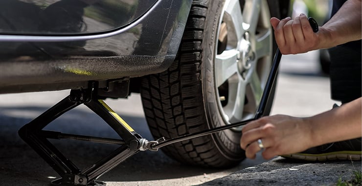 Eine Person hebt gerade ein Auto an, um die Reifen zu wechseln