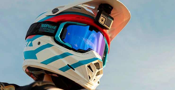 Person mit Motocross-Helm und montierter Actioncam filmt aus der Fahrerperspektive unter freiem Himmel.