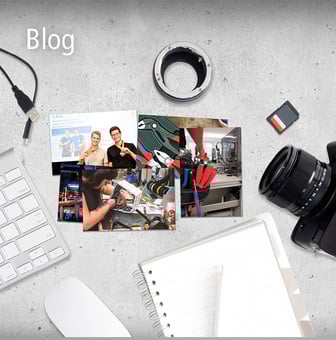 Eine Draufsicht auf einen Schreibtisch mit Kamera, Laptop, Speicherkarte, Notizbuch und einer Collage von Bildern über Technik und Veranstaltungen.