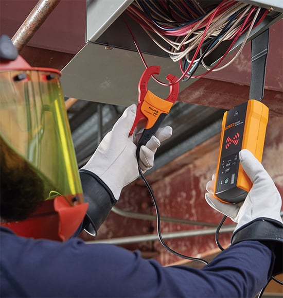 Elektriker nutzt Fluke Zangenmessgerät und kabelloses Fluke Display für elektrische Messungen.