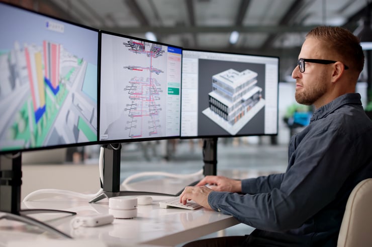 Mitarbeiter arbeitet an BIM-Modellen für Digital Twin im Facility Management auf drei Bildschirmen