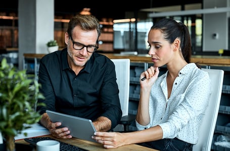 Mitarbeiter betrachten gemeinsam ein Tablet in einem modernen Büro.