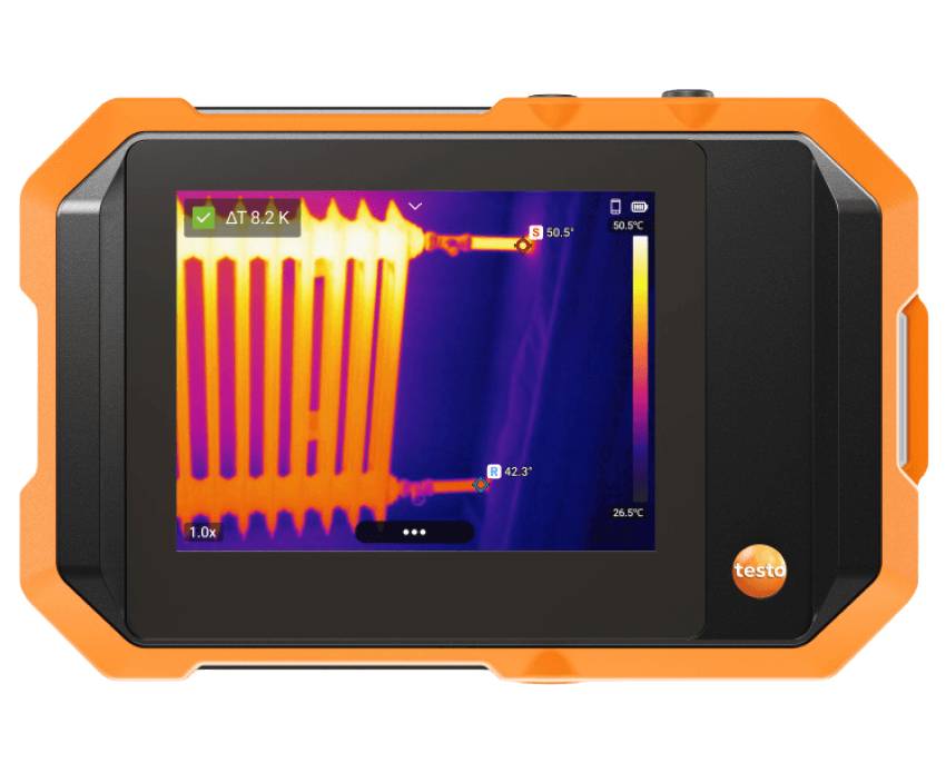 Eine orange-schwarze Wärmebildkamera von Testo mit der Thermografie-Anzeige eines erwärmten Heizkörpers