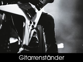 Eine Schwarz-Weiß-Detailaufnahme auf einer Konzertbühne, die den unteren Teil eines Musikers beim Spielen einer markanten, sternförmigen E-Gitarre zeigt.