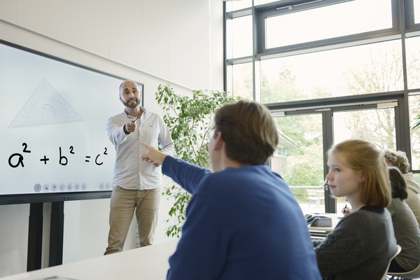 Lehrer erklärt Schülern Mathematik am Legamaster Evolve Interactive Display mit Pythagoras-Formel.