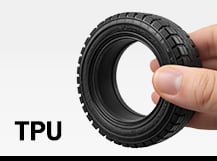 Ein schwarzer, flexibler 3D-gedruckter Reifen, der von einer Hand leicht zusammengedrückt wird, neben dem fettgedruckten Schriftzug „TPU“.