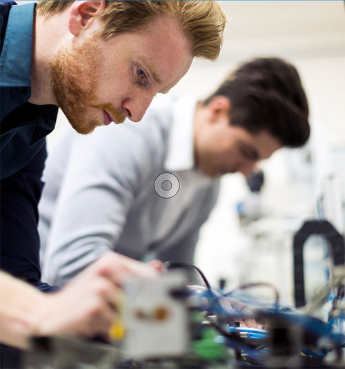 Zwei Techniker konzentrieren sich auf die Arbeit an komplexer Elektronik.
