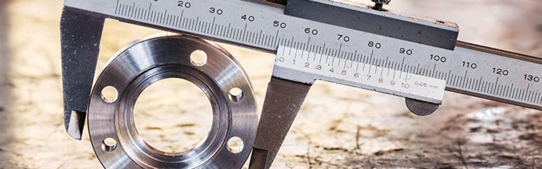 Messschieber misst den Außendurchmesser eines runden Metallflansches.