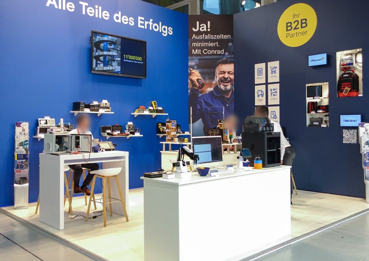 Ansicht des Messestandes von der unteren linken Ecke mit vielen diversen Produkten auf Regalen und Tischen