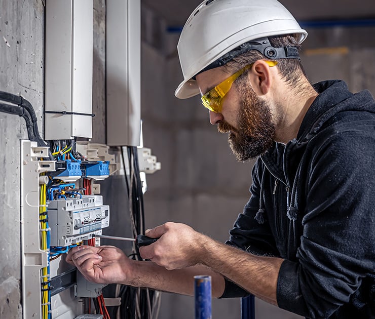 Elektriker installiert Kabel und Komponenten in einem Verteilerkasten.