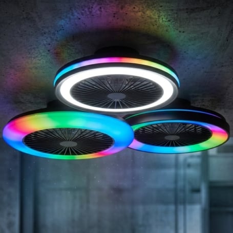 Drei moderne, ringförmige LED-Deckenventilatoren mit farbwechselnden RGB-Lichtringen sind an einer Sichtbetondecke in einem industriell gestalteten Raum montiert und strahlen bunte Lichtreflexionen an die Decke.