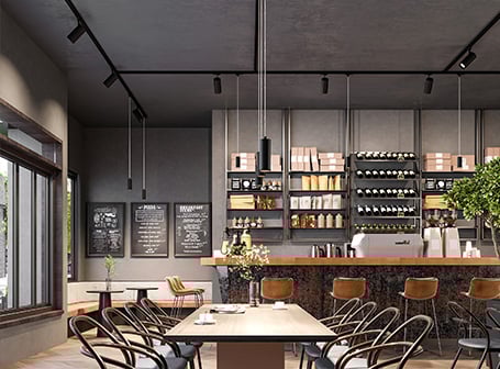 Das Bild zeigt den Innenraum eines stilvollen, modernen Cafés oder Bistros mit einer Bar, Sitzgelegenheiten an Tischen und einer Decke, die mit einem schwarzen 3-Phasen-Schienensystem mit vielen kleinen Strahlern sowie einer einzelnen Hängelampe ausgestattet ist.