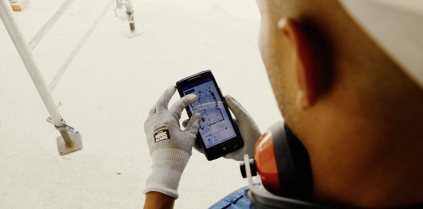 Das Bild zeigt CORE-Z5 ist das erste 5G-Smartphone des französischen Herstellers Crosscall, das speziell für kritische Umgebungen entwickelt wurde. Das Gerät ist in Anwendung in rauher Werkstattumgebung, gehalten von einer jungen Frau bei der Arbeit.