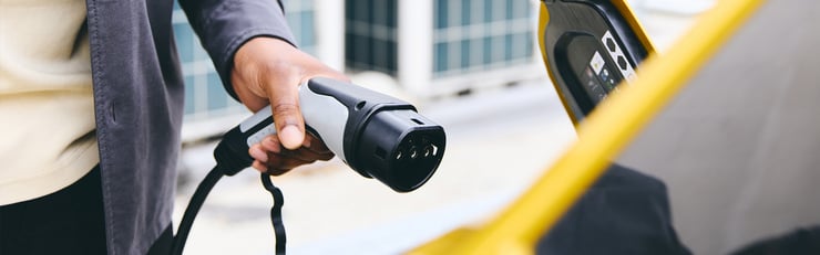 Person hält ein Ladekabel zum Anschluss an ein Elektroauto in der Hand.