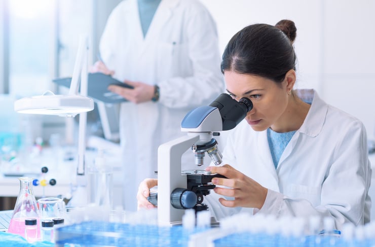 Wissenschaftlerin im Labor betrachtet eine Probe durch ein Mikroskop