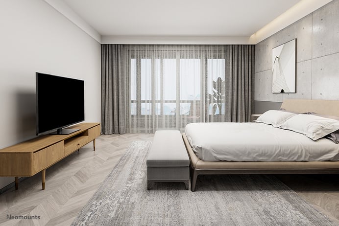 Ein Bild eines modernen Schlafzimmers mit einem großen Bett, Flachbildfernseher und hellen Holzmöbeln.