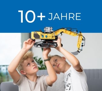 Ein dunkelblaues Banner mit dem Text "10+ JAHRE". Darunter sind zwei Jungen zu sehen, die einen großen, gelben fischertechnik-Bagger von unten betrachten.