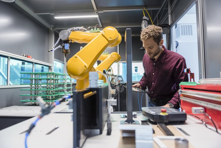 Ein Mann arbeitet in einem Labor mit einem grossen gelben Roboterarm und technischen Geräten.