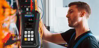 Ein Techniker im Hintergrund arbeitet an einer Verkabelung, während im Vordergrund ein digitaler Kabellängentester der PCE-CLT 100 Serie mit angeschlossenen Messleitungen und Krokodilklemmen präsentiert wird.