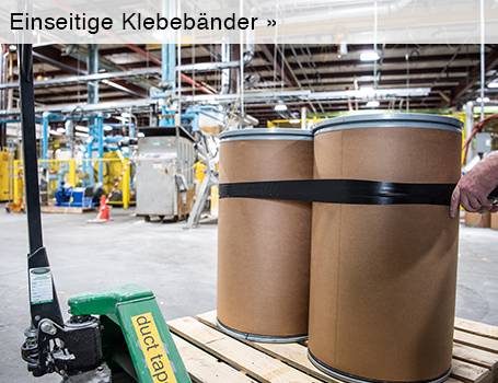 In einem Industriegebäude sind zwei große, zylindrische braune Fässer auf einer Holzpalette zu sehen, die mit einem schwarzen Band zusammengehalten werden, wobei ein Teil eines Hubwagens mit grünem Griff und der Aufschrift "duct tape" im Vordergrund sichtbar ist; der Text "Einseitige Klebebänder »" im oberen Bereich des Bildes weist auf eine Weiterleitung hin.