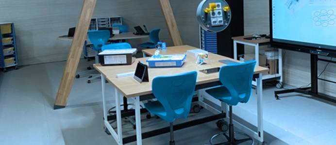 Moderner Klassenraum zum Lernen: Tisch, Smartboard, Tablets und Technikmodule für praktisches Experimentieren.