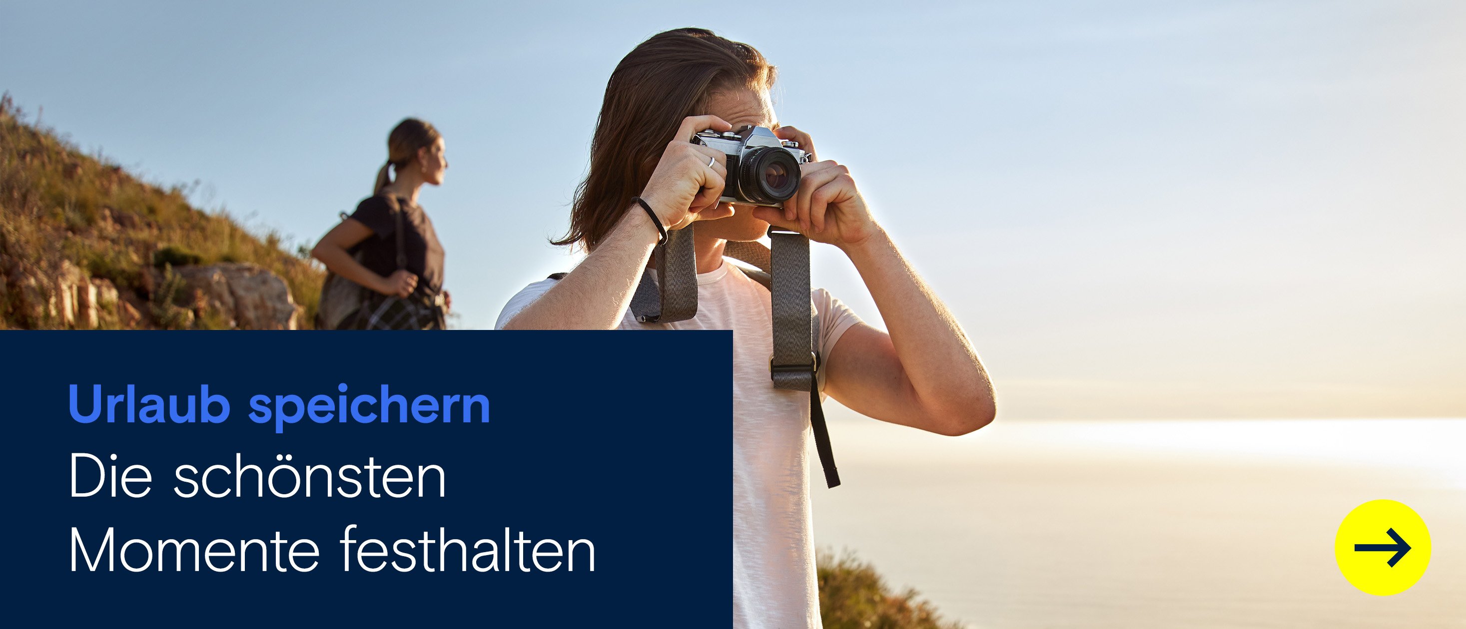 Junger Mann fotografiert mit Kamera in der Natur beim Wandern, Frau im Hintergrund mit Rucksack – Outdoor-Abenteuer und Naturerlebnis bei Sonnenuntergang
