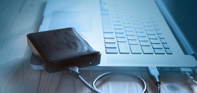 Disque dur externe connecté à un PC portable posé sur un bureau