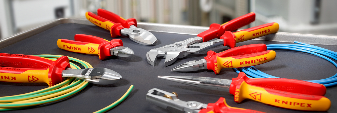 Een collectie geïsoleerde Knipex-gereedschappen, met een verscheidenheid aan VDE-geteste tangen en snijmessen, ontworpen voor veilig werken aan spanningvoerende elektrische componenten.