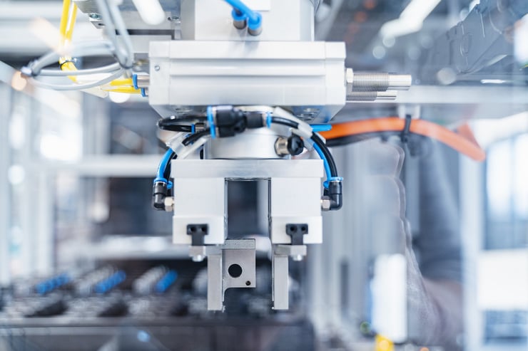 Nahaufnahme einer automatisierten Maschine mit Metallteilen und Kabeln in einer industriellen Umgebung.