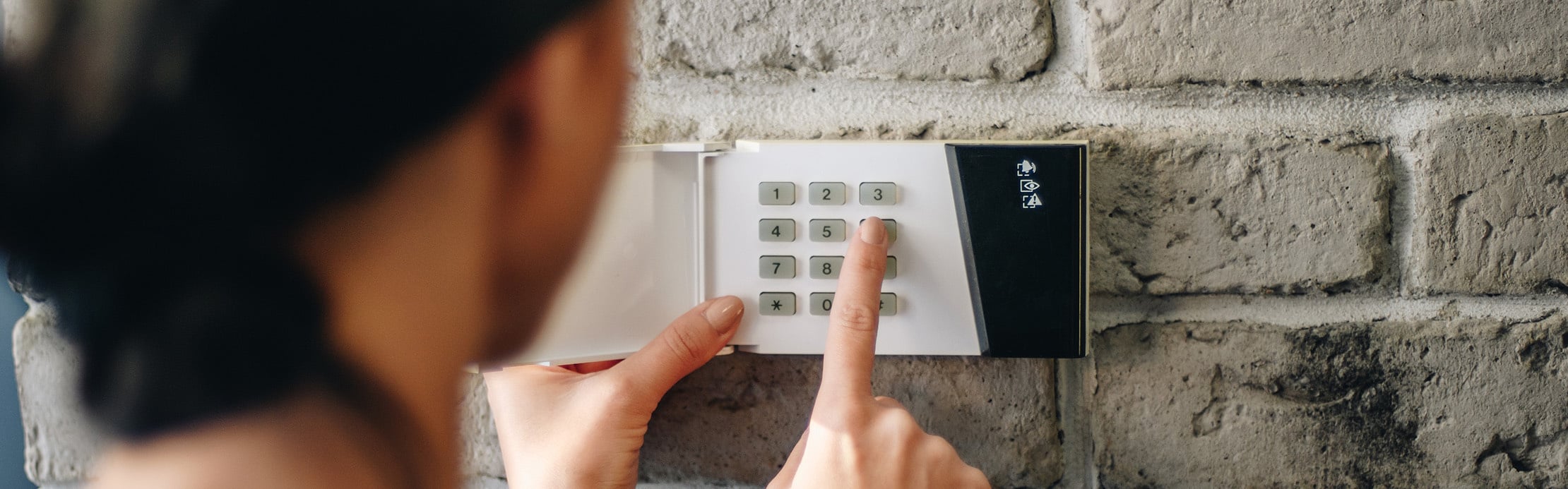 Person gibt einen Sicherheitscode über das Bedienfeld einer Alarmanlage ein.