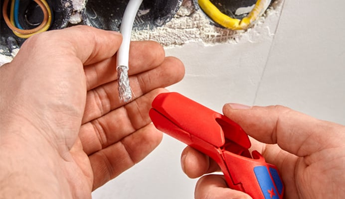 Een assortiment van verschillende kabelstripgereedschappen is op een witte achtergrond gepresenteerd. De gereedschappen variëren in grootte en ontwerp, waaronder sommige met gebogen bladen en andere met ergonomische handgrepen, voor diverse striptoepassingen.