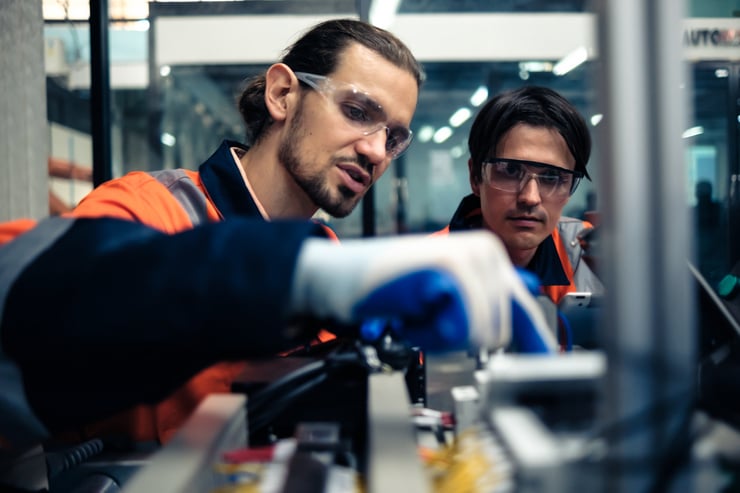 Zwei Fachkräfte in Schutzkleidung arbeiten gemeinsam an einer technischen Anlage - Fachkräftemangel Lösungen