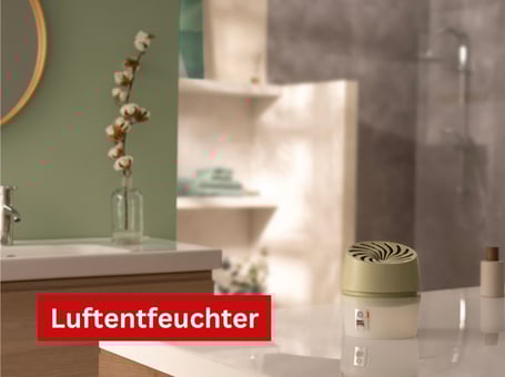 Ein weißer, zylinderförmiger Luftentfeuchter steht auf einem hellen Regal in einem Badezimmer mit Fliesen.