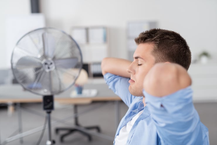Arbeiter sitzt in heissem Raum vor Ventilator